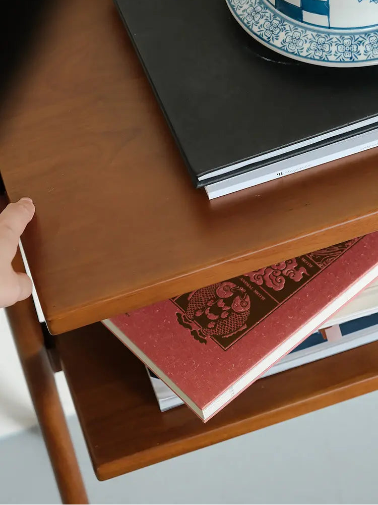 Wooden shelf with books and a decorative plate on a light background