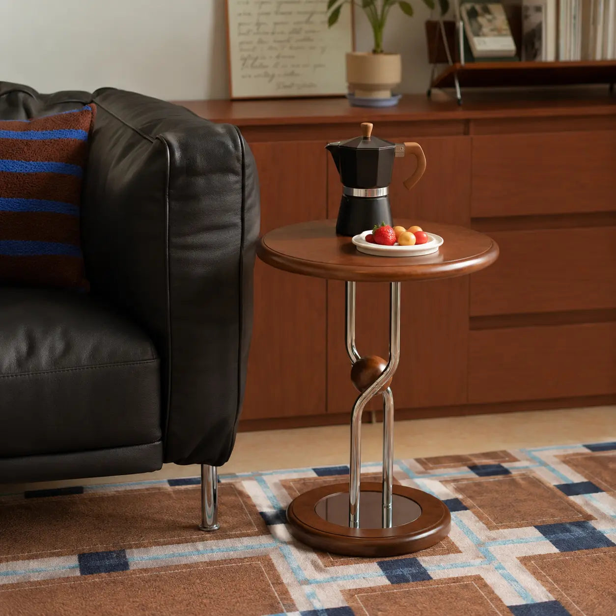 Round wooden side table with a coffee maker and fruit plate in a living room setting.